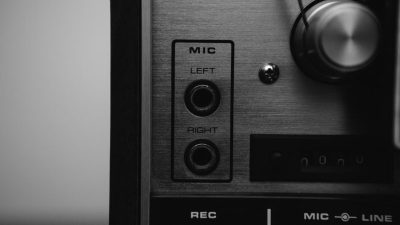 Black and white close-up of a vintage audio mixer with mic inputs, showcasing classic sound technology.